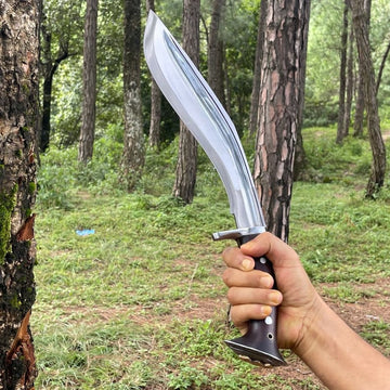Hand holding a kukri knife in a forest setting
